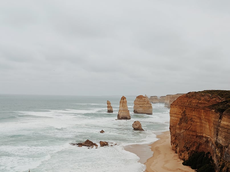 Brown Rock Formation on Sea Shore Under White Clouds